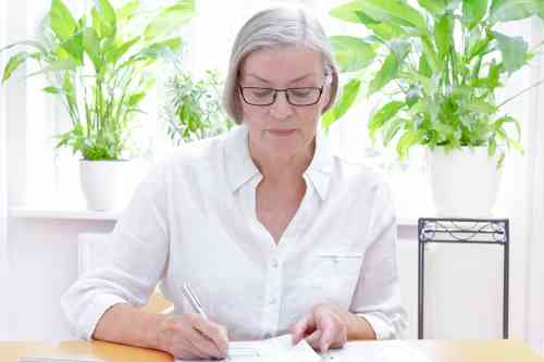 © agenturfotografin - stock.adobe.com Ältere Dame bearbeitet Unterlagen