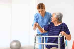 Pflegekraft hilft älterer Frau mit Gehhilfe