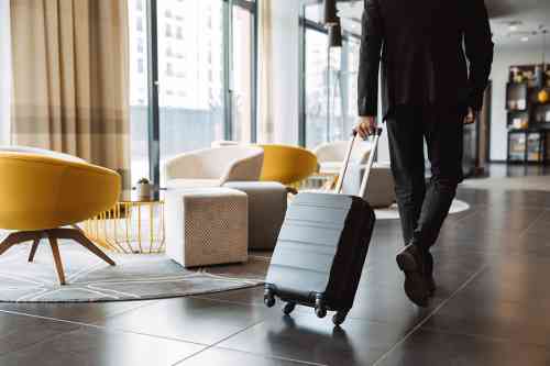 © Drobot Dean - stock.adobe.com Mann zieht Koffer in Hotellobby